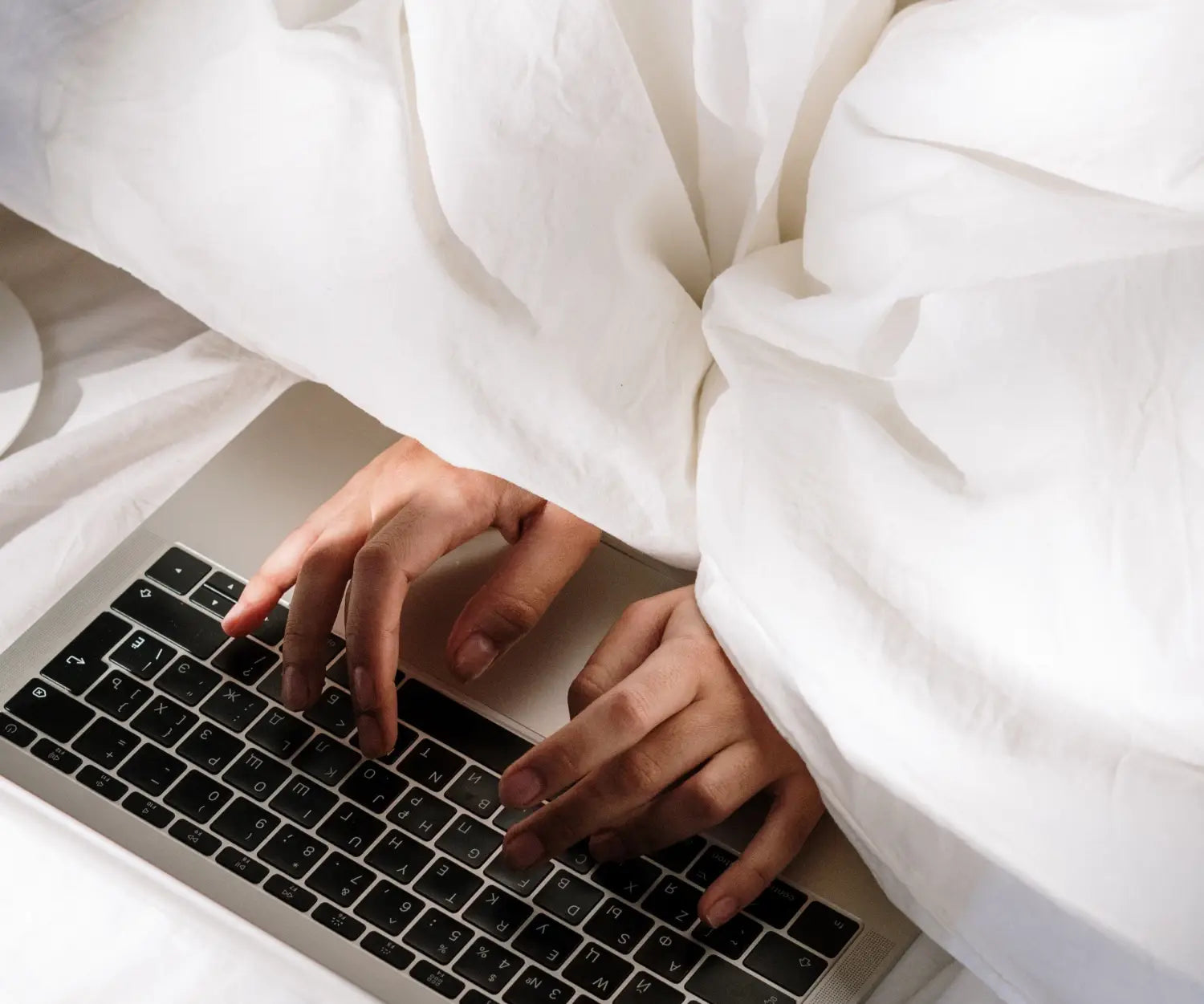 Hands typing on a keyboard in bed Photo by cottonbro from Pexels